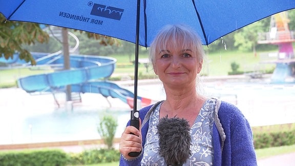 Wettermoderatorin Heike Ziepke mit Regenschirm im Schwimmbad in Saalfeld