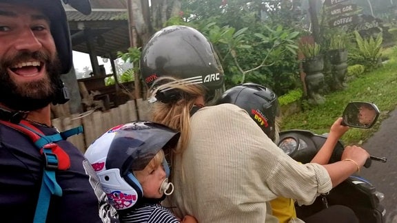 Zwei Eltern sitzen mit ihren zwei Kindern auf einem Moped