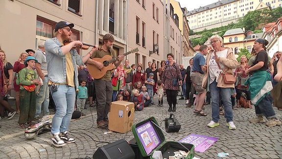 Musikzierende und Zuschauer/-innnen auf der Straße