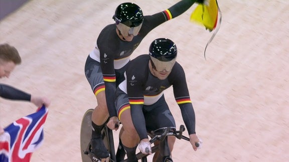 Zwei Personen in Trikots auf Räder bei den Paralympics.