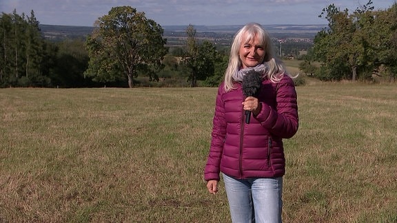 Wetterreporterin Heike Ziepke steht auf einer Wiese