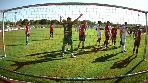 Ein Blick von hinten durch ein Fußballnetz auf die Spieler von Eilenburg und Jena