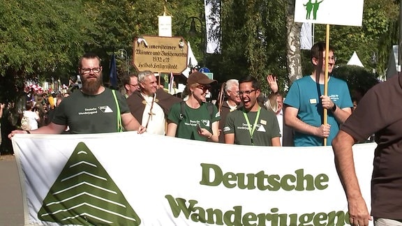 Eine Gruppe von mehreren Menschen hält bei einem Umzug ein Transparent mit der Schrift "Deutsche Wanderjugend"