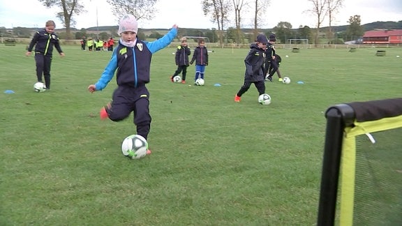 Mädchen schießt Fußball auf ein Tor