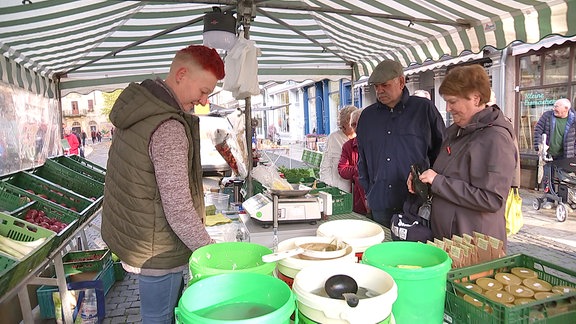 Händler und Kunden an einem Marktstand