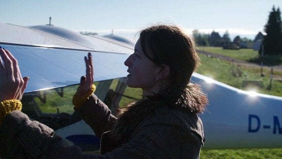 Eine Frau greift an die Flügel eines Leichtflugzeuges