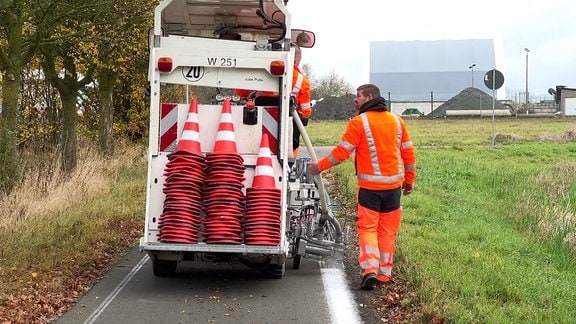 Ein Mann markiert mit einer Maschine die Begrenzung eines Radweges