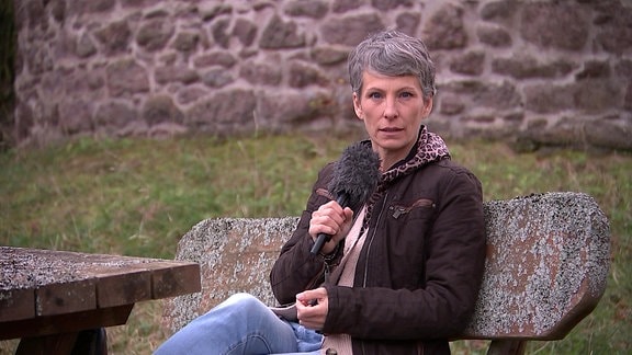 MDR Thüringen Wettermoderatorin Sandra Voigtmann sitzt auf einer Bank aus Stein