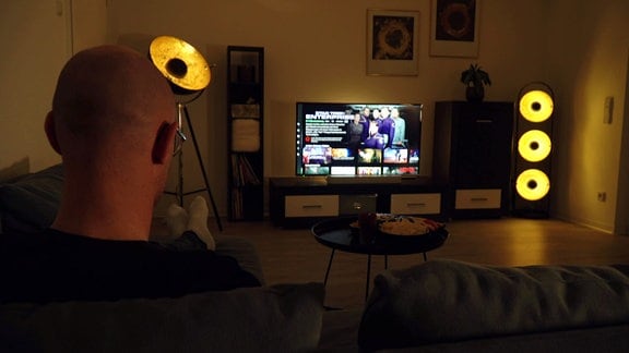 Mann sitzt vor Fernseher