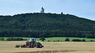Ein Traktor auf einem Feld vor dem Kyffhäuser-Denkmal