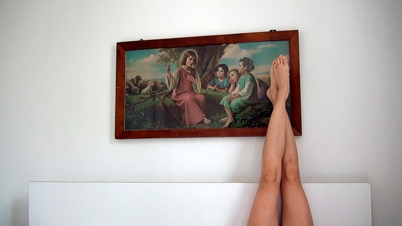 Frauenbeine sind auf eine Wand mit Bild gelegt.