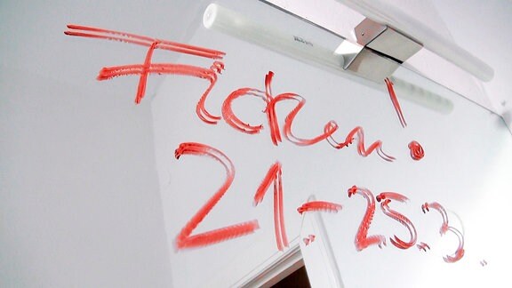 Auf einem Spiegel steht mit Lippenstift geschrieben "Ficken! 21.-25.3.".
