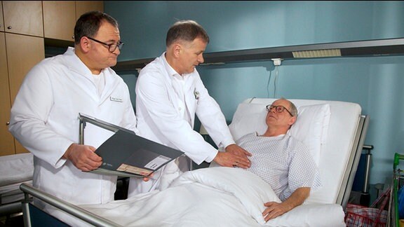 Dr. Heilmann und Pfleger Brenner untersuchen den Obdachlosen Olaf am Krankenbett