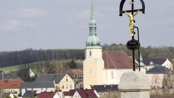 Das Dorf Crostwitz bei Kamenz mit einem Jesuskreuz und den Blick auf die Dorfmitte und die Pfarrkirche. 