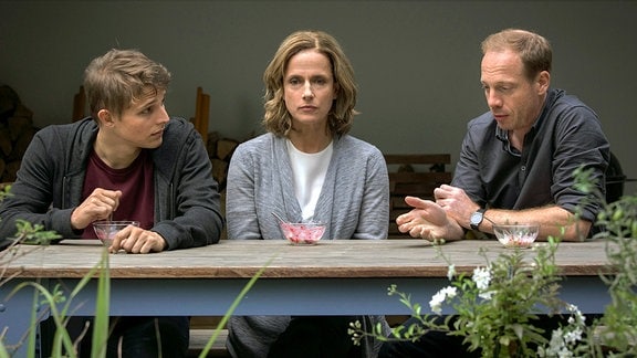 Milan (Merlin Rose), Susann (Claudia Michelsen), Gustav (Johann von Bülow) sitzen an einem Tisch.