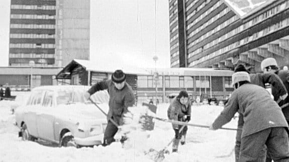 Menschen schippen Schnee vor einem Hotel