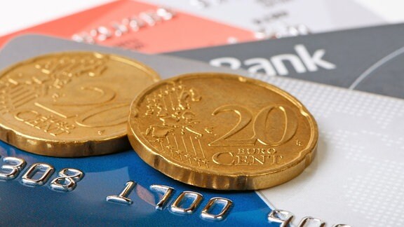 zwei Euro Münzen liegen auf einem Stapel Kreditkarten.