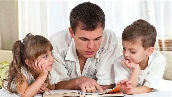 Ein Mann und zwei Kinder lesen ein Buch