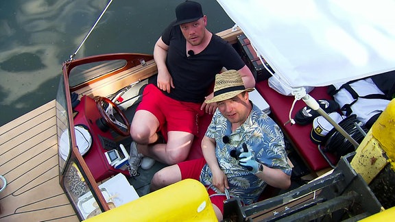 Zwei Männer sitzen in einem Motorboot.