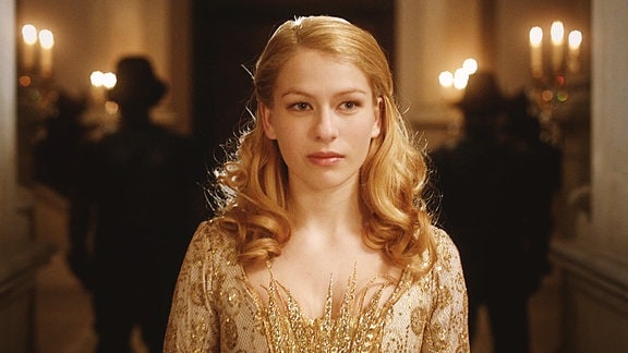 Eine junge Frau mit goldenen Haaren trägt ein goldenes Kleid