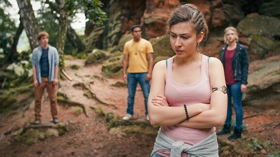 Mädchen steht im Vordergrund einer Felswand mit drei Jugendlichen