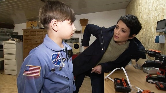 Ein Junge in einem NASA-Anzug unterhält sich mit einer Frau.