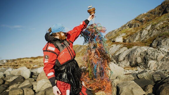 Filmemacher Steffen Krones auf den Lofoten mit einer GPS-Boje, die sich auf  ihrer Reise in Plastiknetzen verfangen hat.