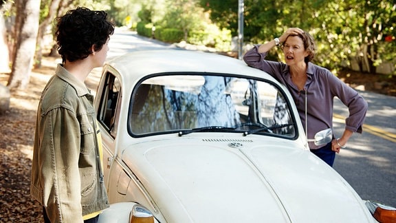 Dorothea (Annette Bening) steht mit ihrem Sohn Jamie (Lucas Jade Zumann) an einem weißen VW "Käfer".