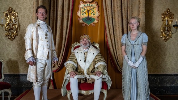 Prinz Lassmann (Stefan Gorski), auf dem Thron König Albert (Dominick Raacke) und Helene (Caroline Hellwig, v.l.) im Schloss.