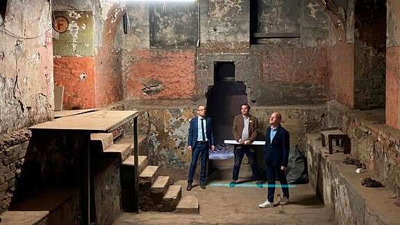 Drei Männer stehen in der ehemaligen Defensionskaserne auf dem Petersberg. 