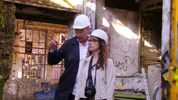 Eine Frau und ein Mann besichtigen ein verfallendes Gebäude