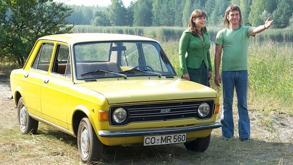Elke (Katharina Wackernagel) und Gregor (Peter Schneider) stehen mit einem "Lada" an einem See.