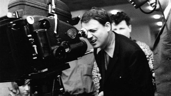 Alexander Kluge blickt als Regisseur durch eine Kamera