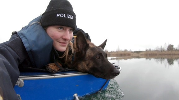 Eine Hundeführerin übt mit ihrem Polizeihund das fahren im Boot.