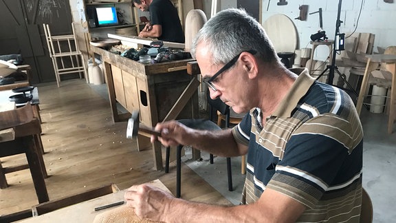 Ein Mann arbeitet mit einem Hammer an Holz.