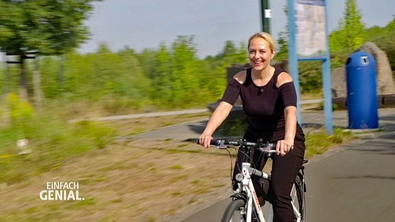 Eine blonde Frau fährt lächelnd Fahrrad.