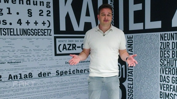 Ein Mann steht vor einer Wand die mit Begriffen tapeziert ist.