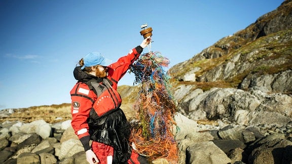 Filmemacher Steffen Krones auf den Lofoten mit einer GPS-Boje, die sich auf ihrer Reise in Plastiknetzen verfangen hat.