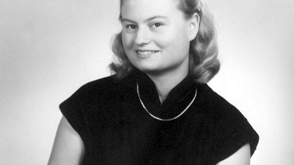 Ein schwarz-weiß Portrait von Hannelore Kohl, die freundlich in die Kamera lächelt.