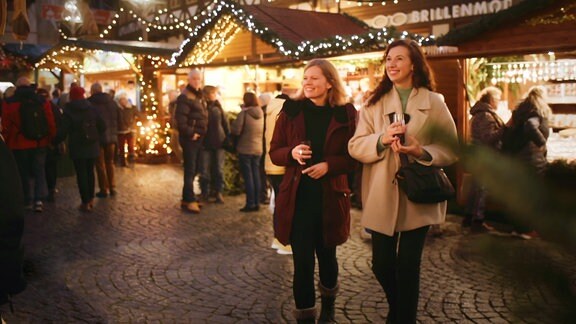 Zwei Frauen schlendern über einen Weihnachtsmarkt.