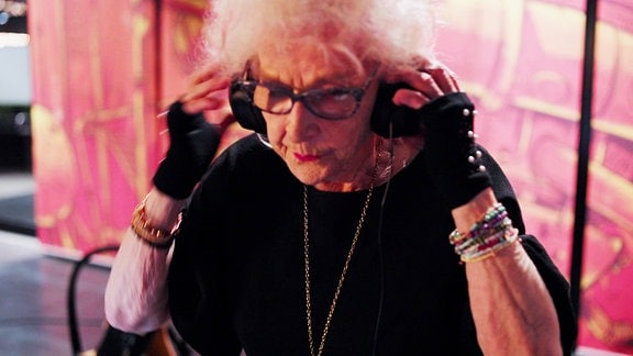 Ältere Dame mit Kopfhöreren am DJ Pult