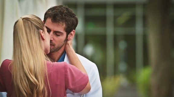 Eine Ärztin küsst ihren Kollegen