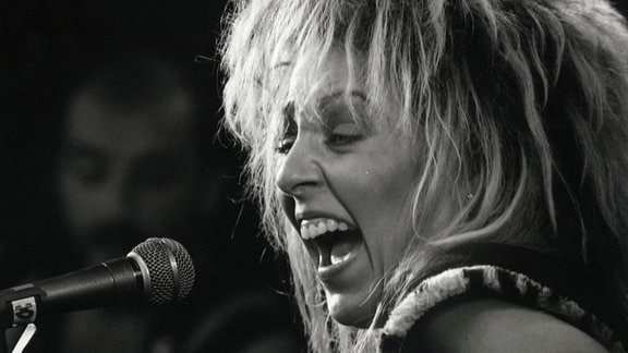 Schwarz-weiß-Bild von Tamara Danz, die leidenschaftlich ins Mikrofon singt.