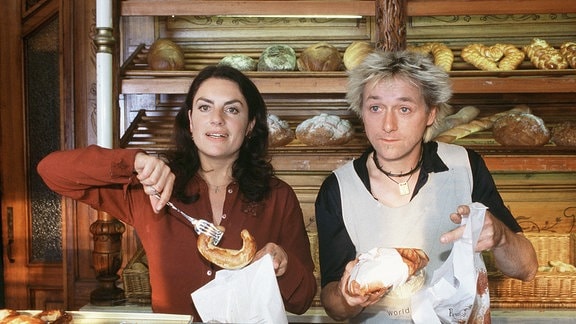 Eine Frau und ein Mann beim Bedienen hinter einer Bäckertheke.