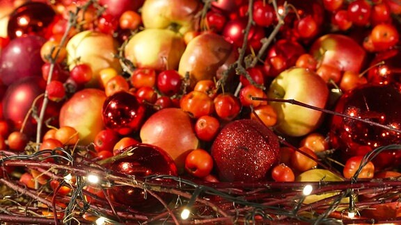Ein Gesteck mit Früchten und Weihnachtskugeln.