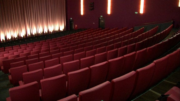 Ein leerer Kinosaal mit roten Sitzen.