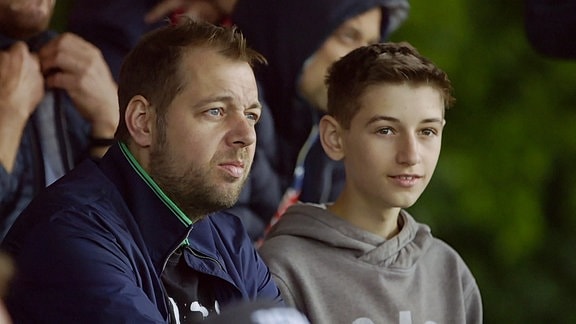 Ein Mann und ein Junge sitzen in einem Fußballstadion.