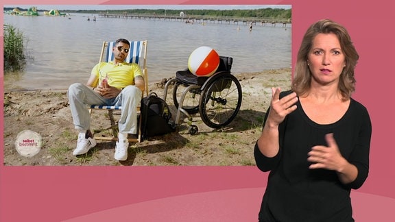 Ein dunkelhaariger Mann sitzt an einem Strand in einem Stuhl neben einem Rollstuhl mit rot-weiß-gelbem Wasserball und davor steht eine Gebärdinsprecherin.