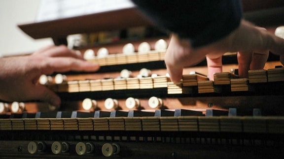 Zwei Hände spielen auf den Tasten einer Orgel.