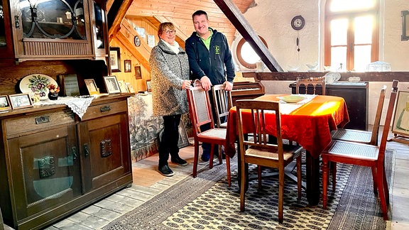 Eine Frau und ein Mann stehen in einem historisch eingerichteten Dachgeschoss.